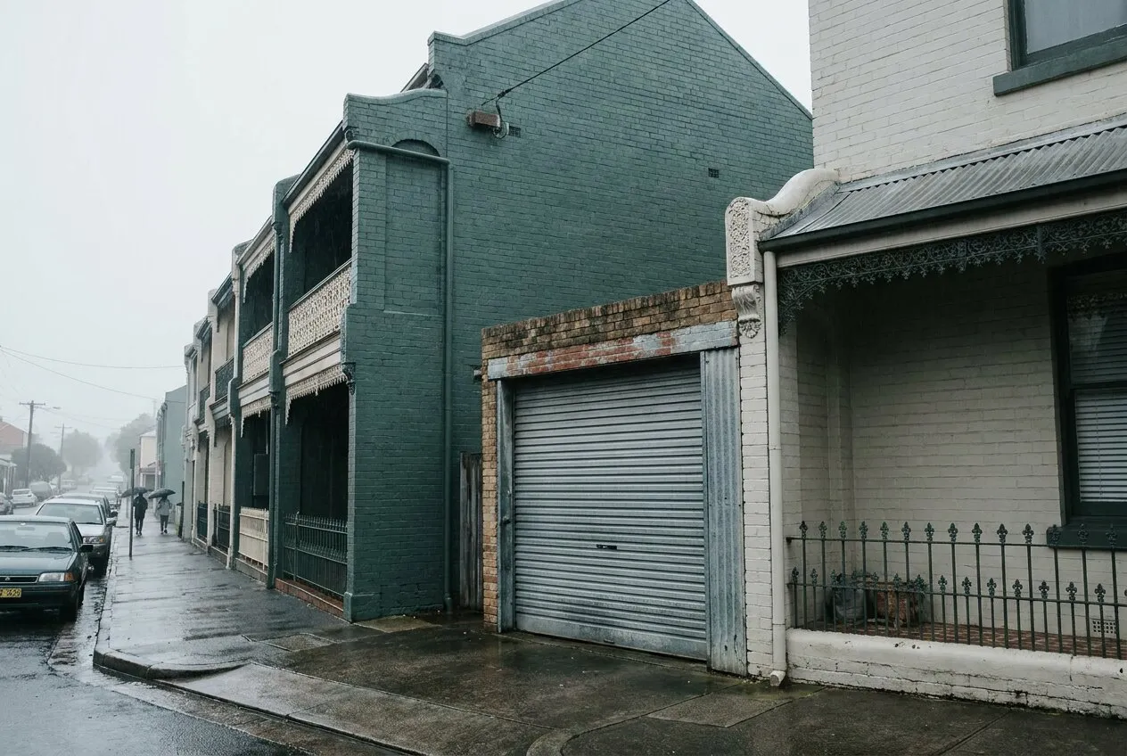 A Cooks Hill terrace street with a narrow older roller door between two terraces